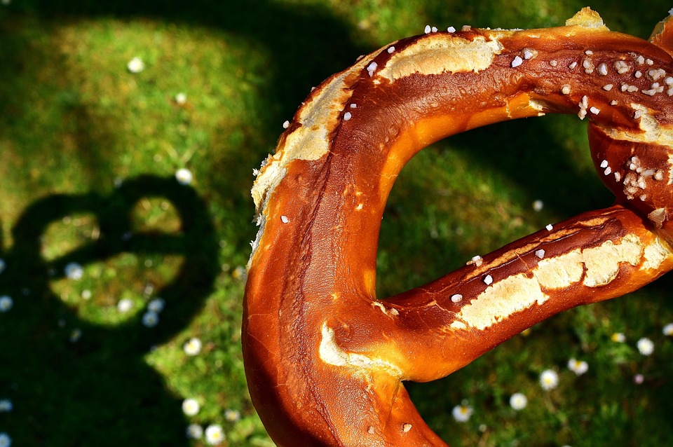Eine Brezel wirft einen Schatten auf die grüne Wiese